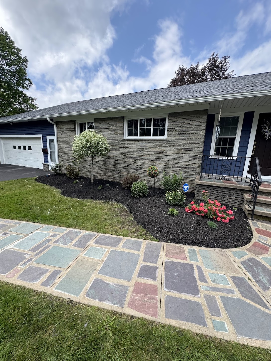 Backyard patio with wet stamped concrete and retaining wall, bordered by straw for new lawn installation.
