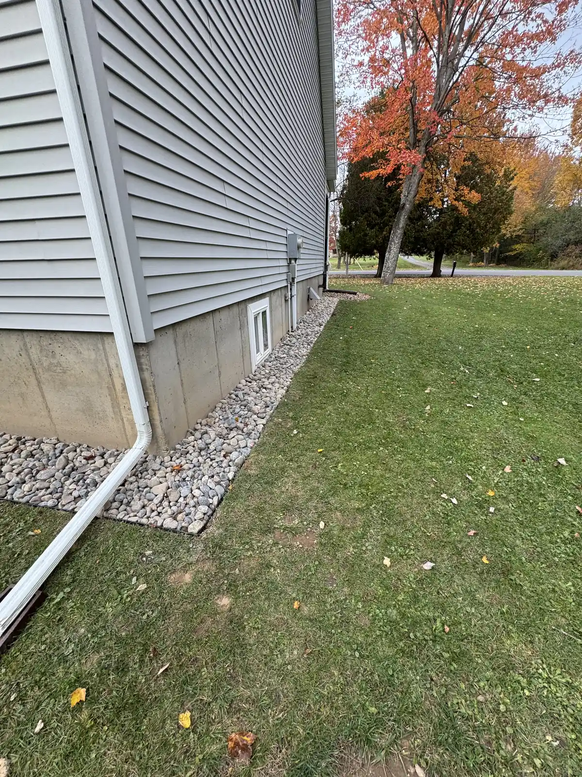 Completed residential drainage system using decorative river rock around the foundation for improved water runoff control.


