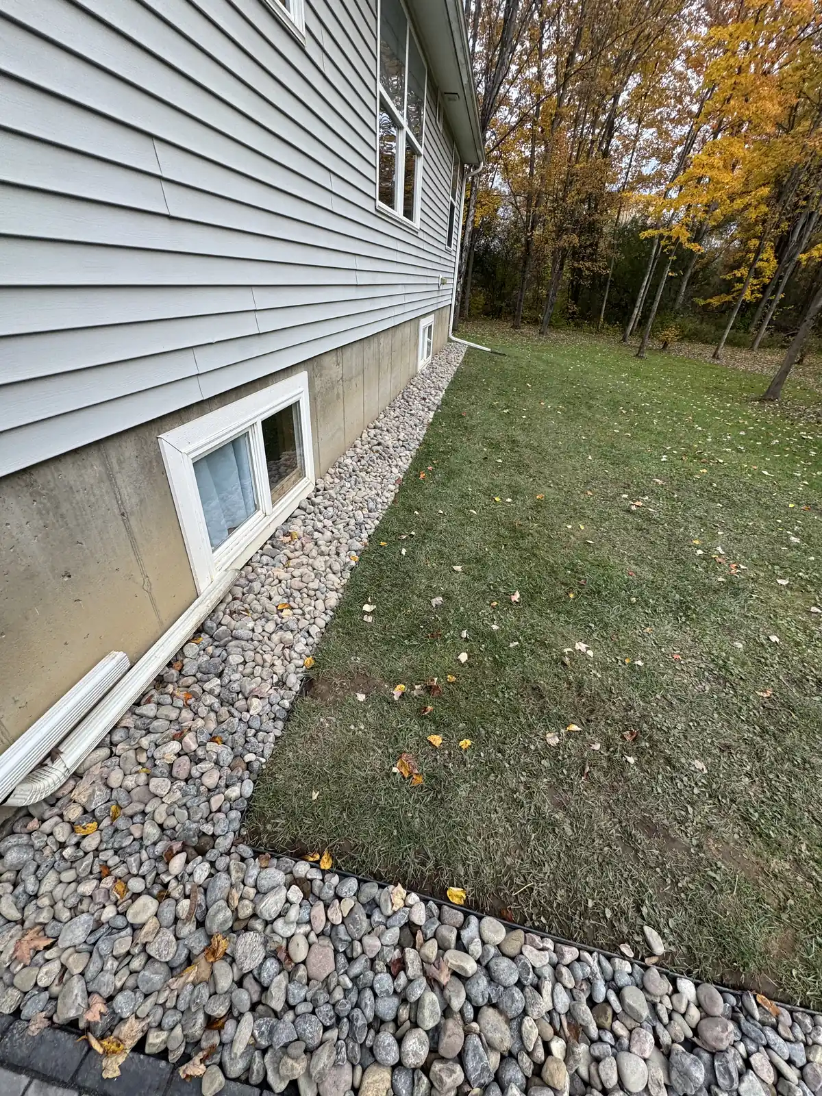 Drainage gravel placed along a house foundation to prevent water accumulation and protect basement windows.
