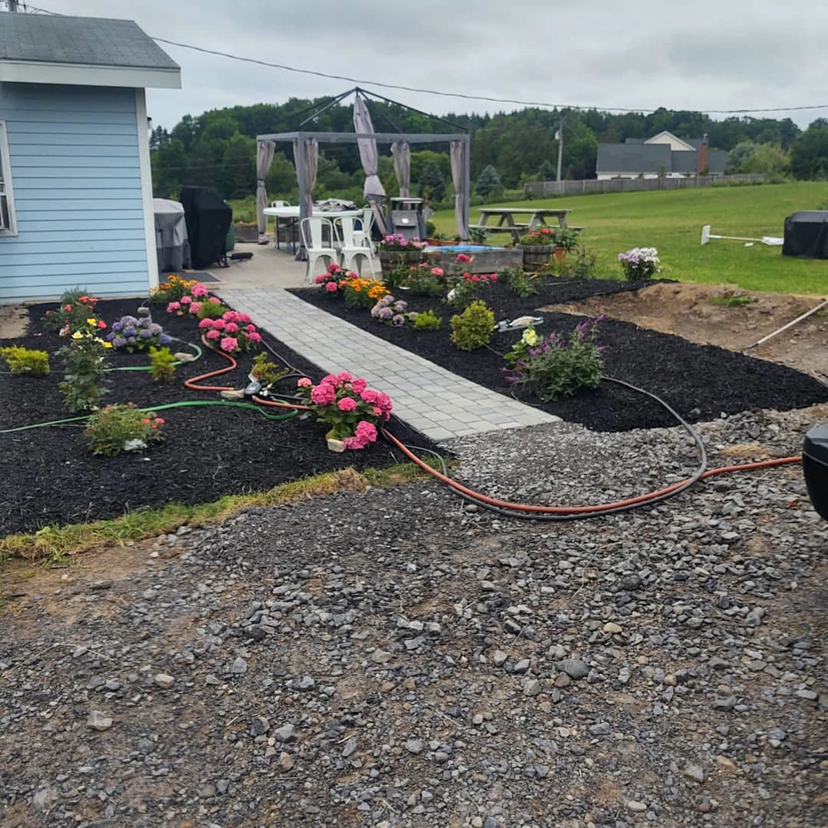  Front yard landscaping featuring decorative river rock bed, curved concrete walkway, and sparse ornamental plants.
