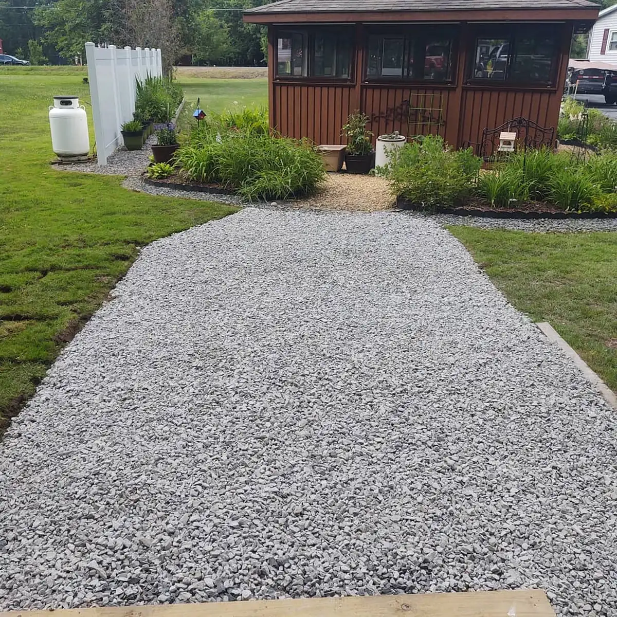 Landscaping project with raised garden beds and new stone paver patio, surrounded by greenery and trees.
