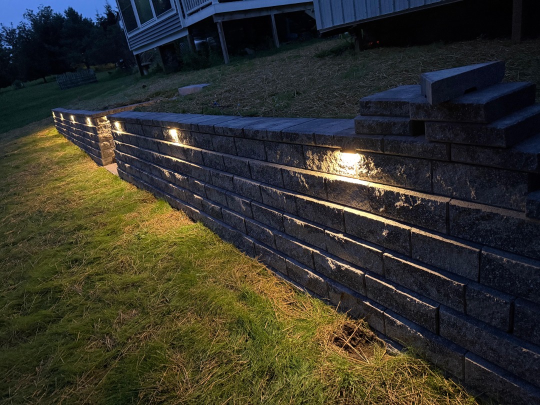  Patio retaining wall with integrated landscape lighting for nighttime ambiance and safety.