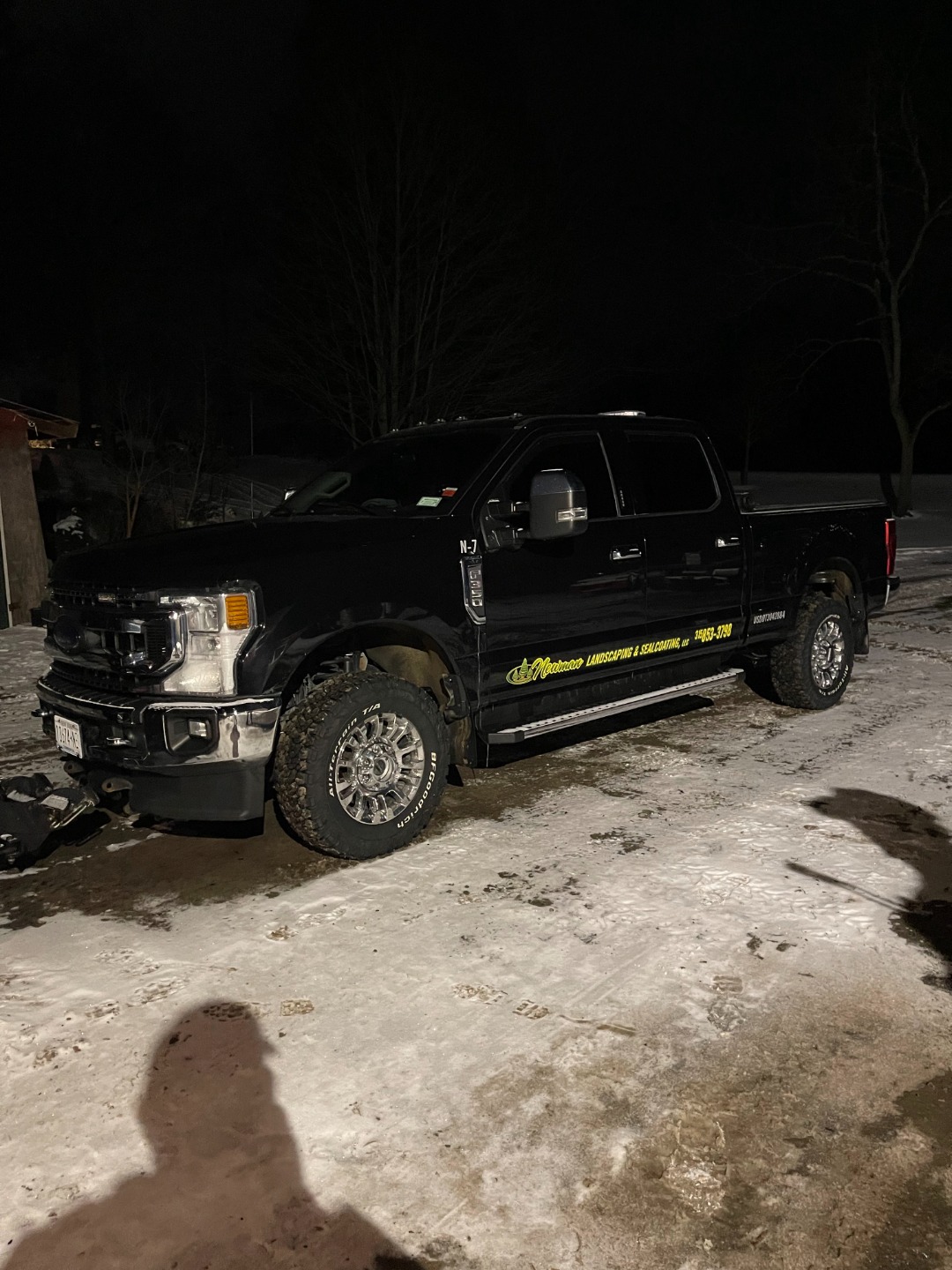 Snow removal vehicle parked at night, showcasing equipment readiness for plowing and salting during winter conditions.