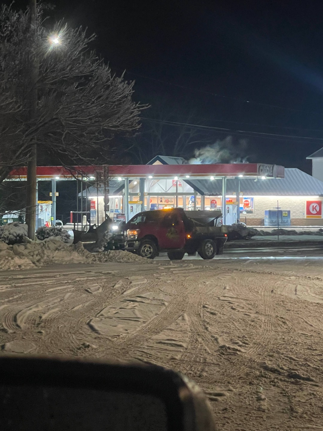 Nighttime snow removal at a gas station, emphasizing 24/7 winter safety and plowing operations in Utica commercial areas.