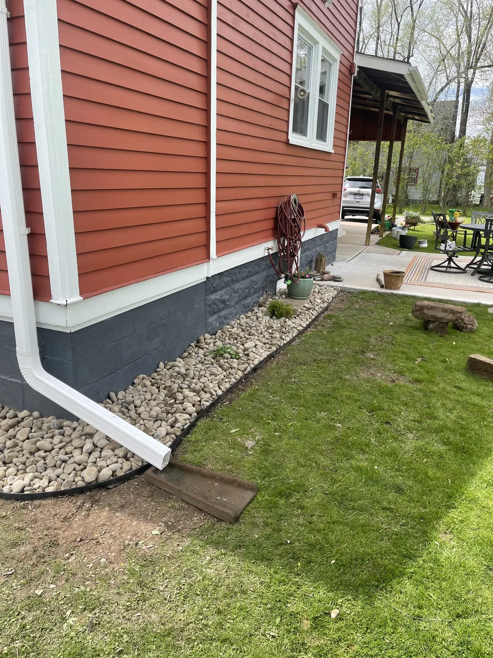 Downspout extension and stone trench supporting proper drainage around patios and walkways in winter climates.