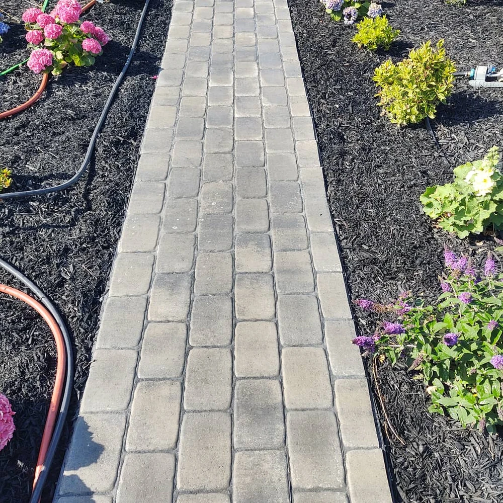 Close up of a straight pavers walkway bordered by mulch beds showing a safe surface.