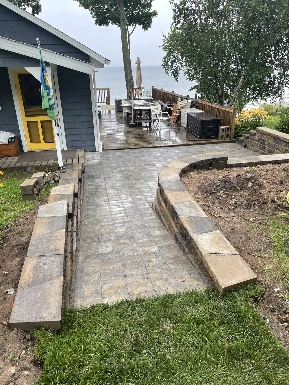 Newman Landscaping hardscaping utica ny 1 - Newman Landscaping & Excavating Paver hardscaping walkway with retaining walls leads from the lawn to a lakeside deck and patio.
