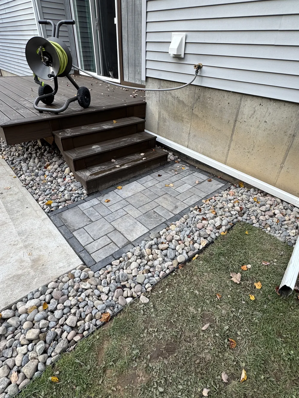 Newman Landscaping outdoor living spaces westmoreland ny - Newman Landscaping & Excavating Paver hardscaping landing with river rock border improves access at deck steps beside the house.